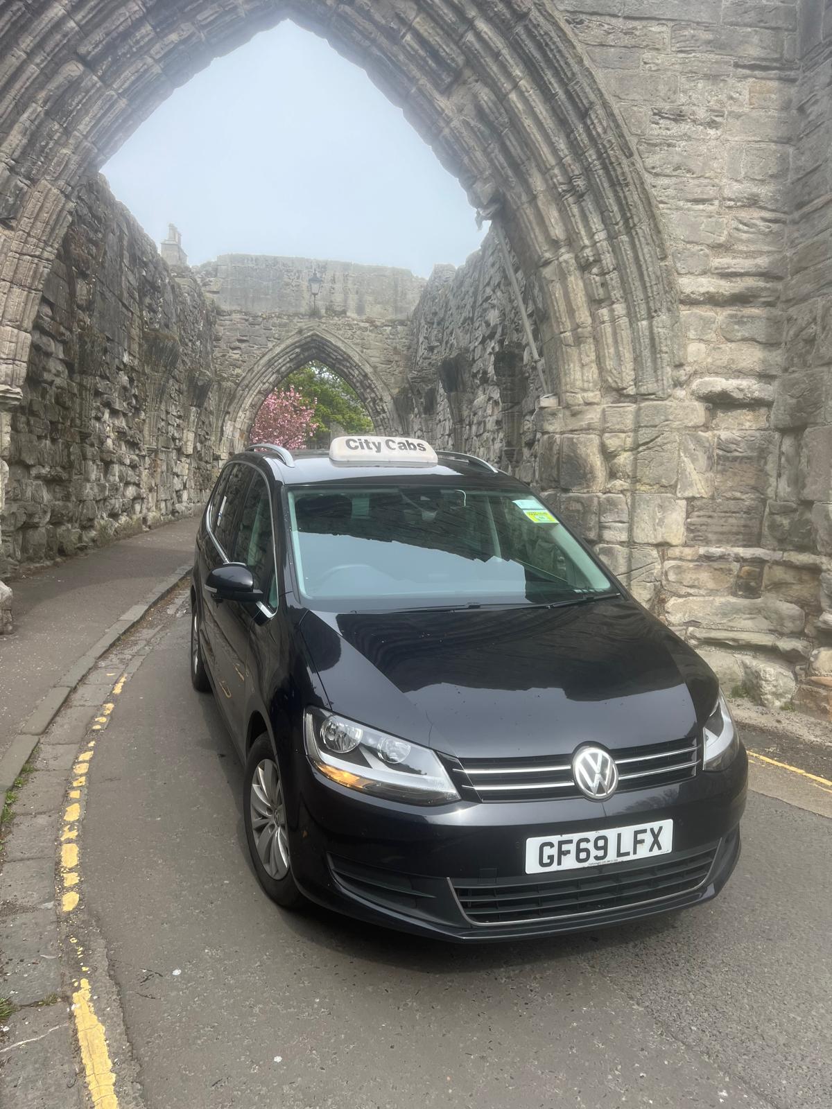 Black VW Sharan taxi under a St Andrews stone archway